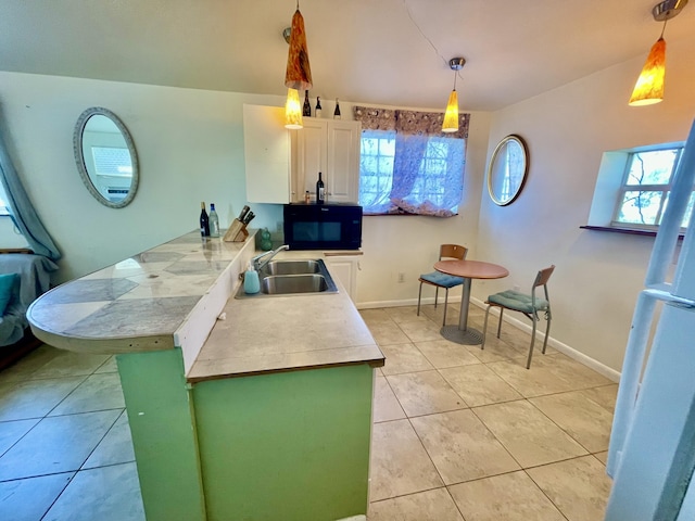 kitchen featuring sink, light tile patterned floors, white refrigerator, decorative light fixtures, and white cabinetry