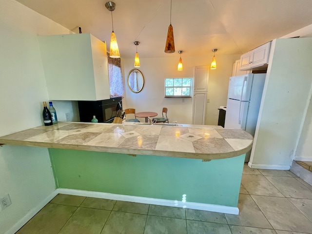 kitchen featuring kitchen peninsula, decorative light fixtures, white cabinetry, and white fridge