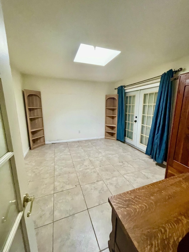 tiled spare room featuring french doors and a skylight