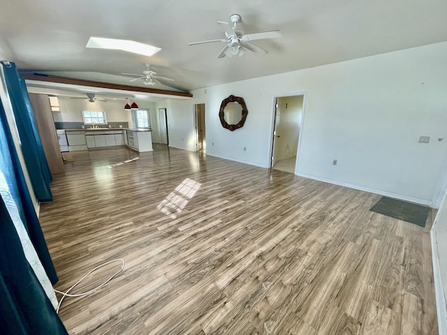 unfurnished living room with vaulted ceiling with skylight and wood-type flooring