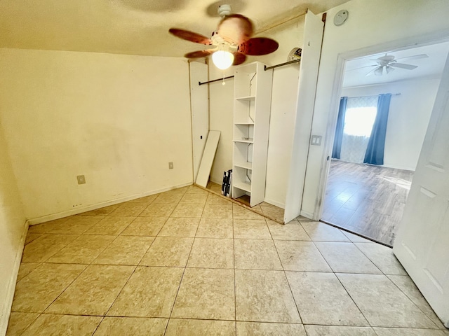 empty room with ceiling fan and light tile patterned floors