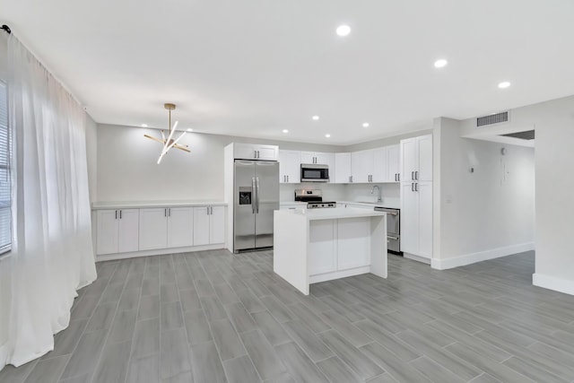 kitchen featuring light countertops, a sink, a kitchen island, stainless steel appliances, and visible vents