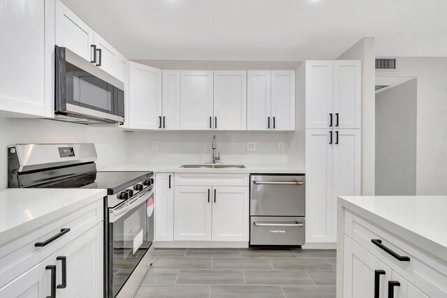 kitchen with white cabinetry, hanging light fixtures, stainless steel fridge, a kitchen island, and a notable chandelier