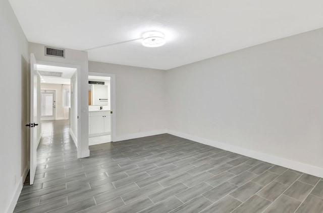 spare room featuring wood tiled floor, baseboards, and visible vents