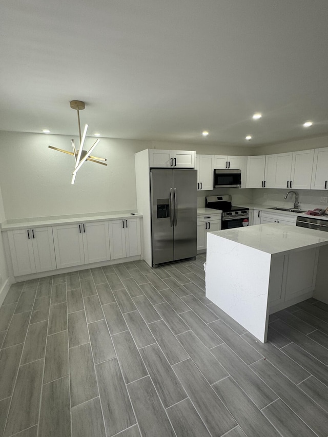 kitchen with white cabinets, appliances with stainless steel finishes, an inviting chandelier, and sink