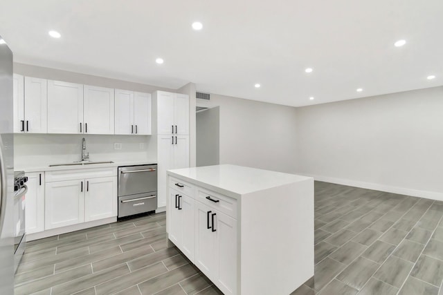 kitchen with sink, stainless steel stove, white cabinets, and a kitchen island