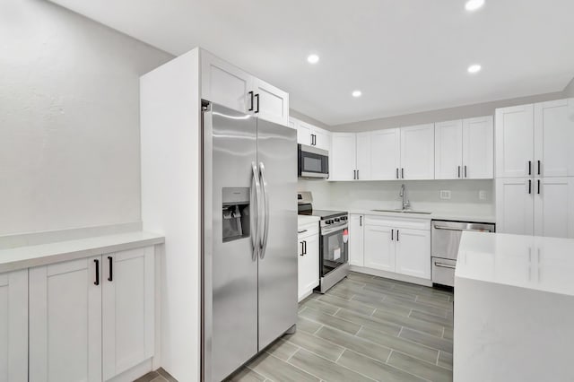 kitchen with light countertops, white cabinets, stainless steel appliances, recessed lighting, and a sink