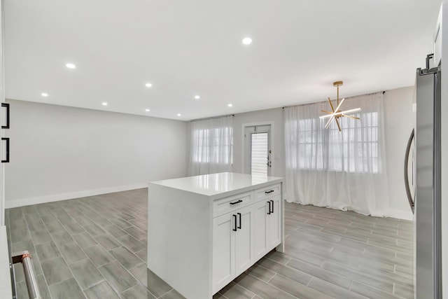 kitchen with light countertops, freestanding refrigerator, baseboards, white cabinets, and recessed lighting