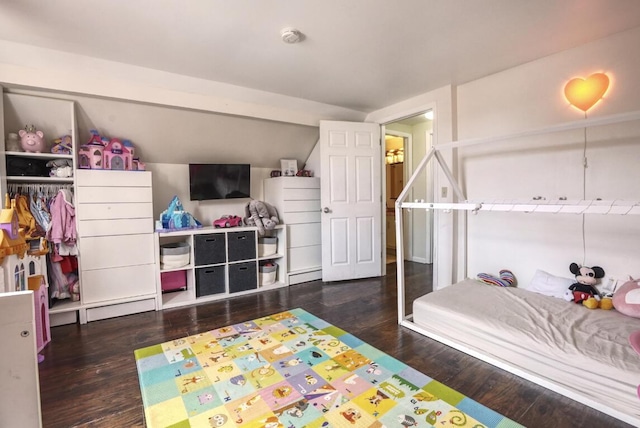 bedroom with a baseboard heating unit, lofted ceiling, and wood finished floors