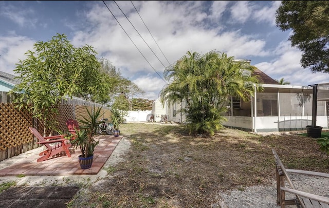 view of yard featuring a patio area, a fenced backyard, and a sunroom