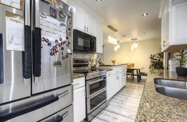 kitchen with dark stone counters, stainless steel appliances, hanging light fixtures, and white cabinets