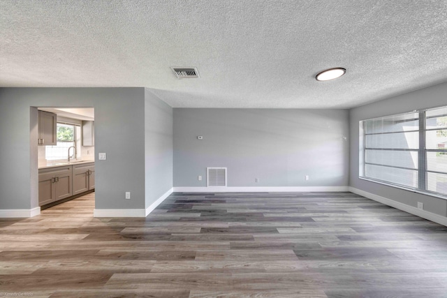 unfurnished room featuring sink, a textured ceiling, and dark hardwood / wood-style floors