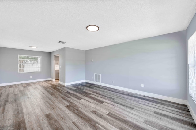 empty room featuring a textured ceiling and light hardwood / wood-style flooring