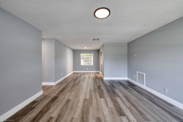 spare room with a textured ceiling and hardwood / wood-style flooring