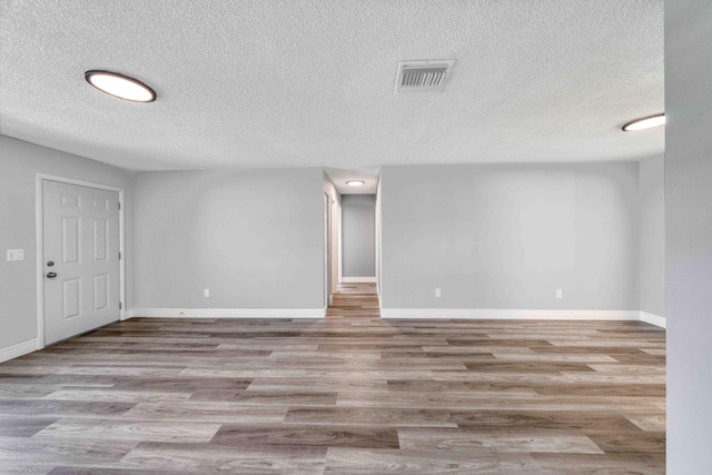 empty room with a textured ceiling and light wood-type flooring