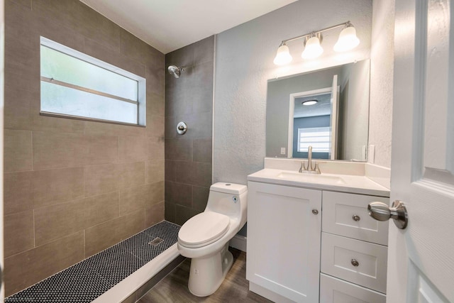 bathroom featuring a tile shower, vanity, toilet, and hardwood / wood-style floors