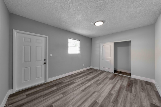 unfurnished bedroom featuring a textured ceiling, hardwood / wood-style floors, and a closet