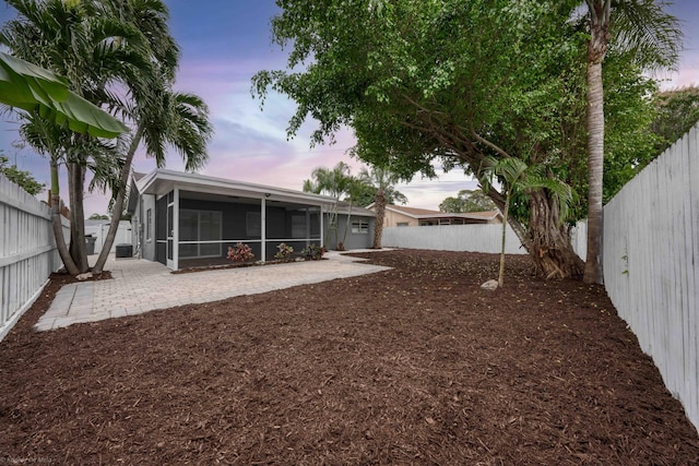 yard at dusk with a patio area and a sunroom