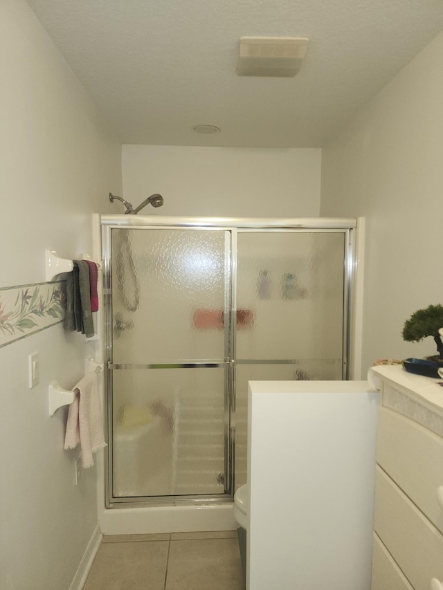 bathroom featuring tile patterned flooring, vanity, toilet, and an enclosed shower