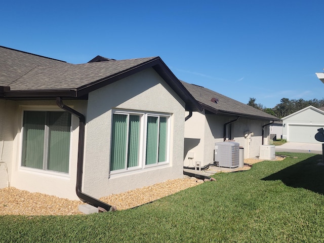 view of side of property with an outbuilding, central AC, and a lawn