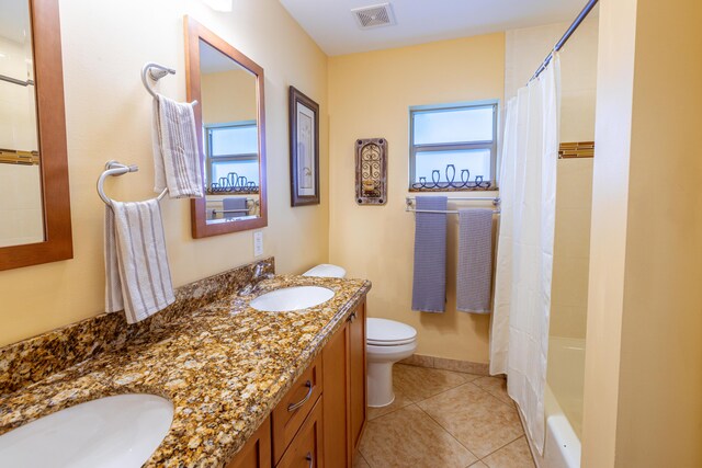 full bath featuring toilet, tile patterned flooring, double vanity, and baseboards