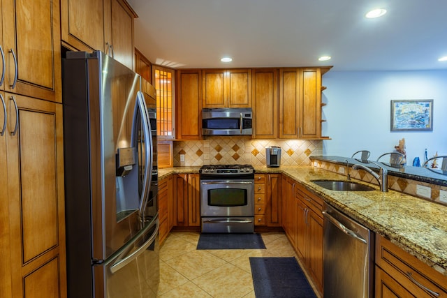 kitchen featuring stainless steel appliances, a sink, brown cabinetry, and recessed lighting