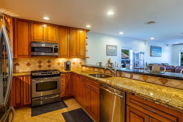 kitchen with appliances with stainless steel finishes, tasteful backsplash, recessed lighting, brown cabinetry, and light stone counters