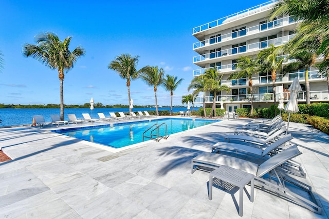 view of swimming pool featuring a patio and a water view