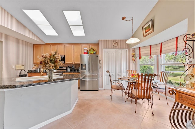 kitchen with light tile patterned floors, appliances with stainless steel finishes, light brown cabinetry, pendant lighting, and sink