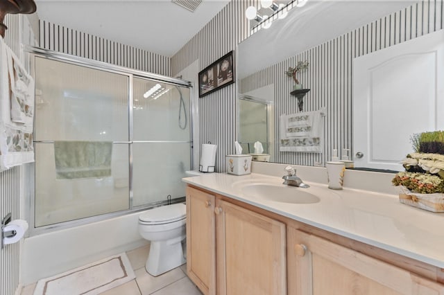 full bathroom featuring toilet, bath / shower combo with glass door, tile patterned floors, and vanity