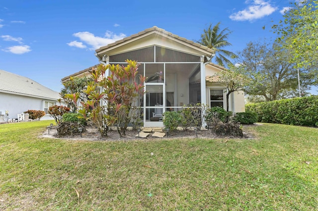 rear view of property featuring a sunroom and a lawn