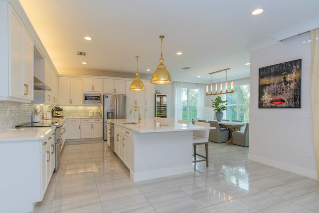 kitchen with pendant lighting, sink, white cabinetry, an island with sink, and stainless steel appliances