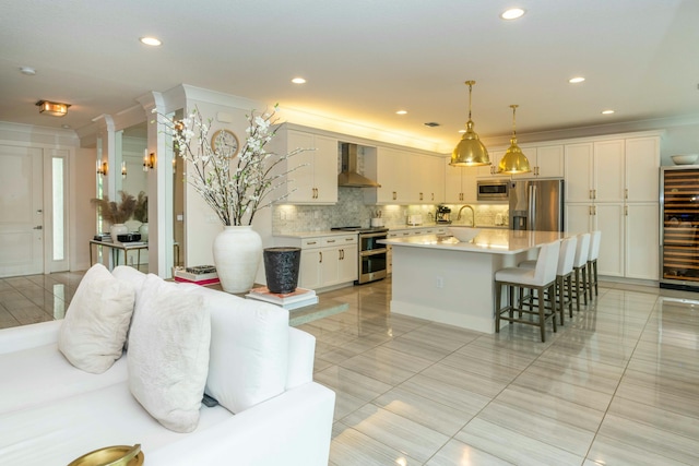 kitchen featuring appliances with stainless steel finishes, tasteful backsplash, hanging light fixtures, a kitchen island, and wall chimney exhaust hood