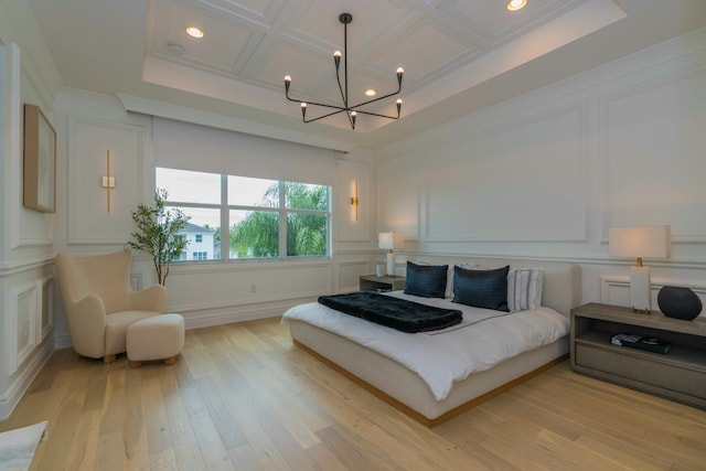 bedroom with light wood-type flooring, an inviting chandelier, beamed ceiling, and coffered ceiling