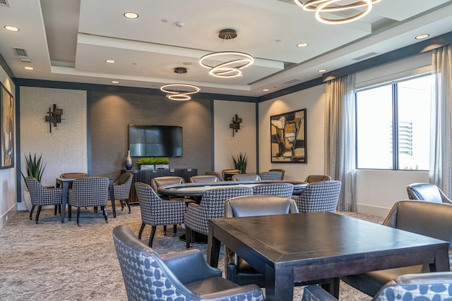 dining room with an inviting chandelier, light colored carpet, and a tray ceiling