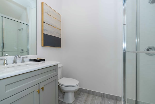 bathroom featuring toilet, vanity, and a shower with shower door