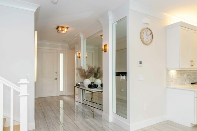 tiled foyer with ornamental molding and decorative columns