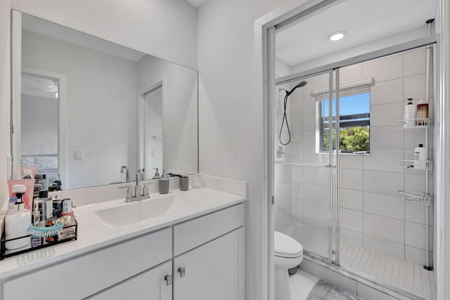 bathroom with a shower with shower door, vanity, and toilet