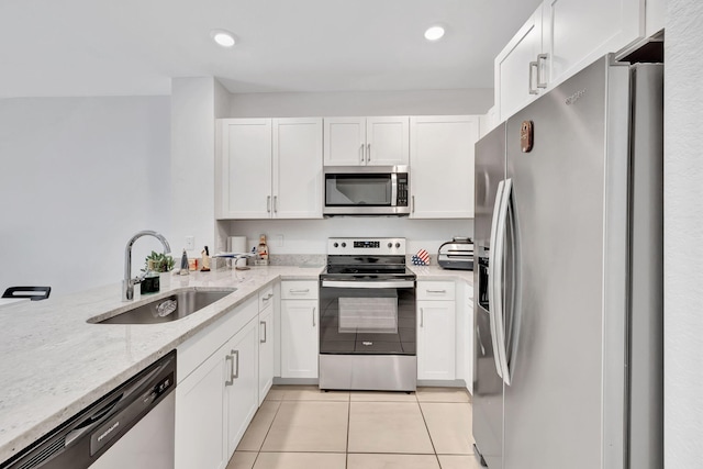 kitchen with light stone counters, stainless steel appliances, white cabinetry, and sink