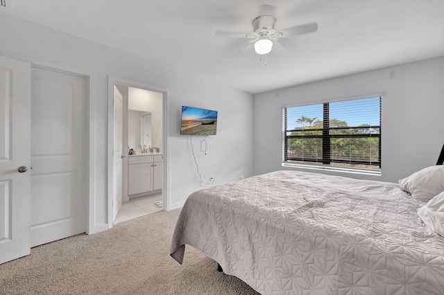 bedroom with light colored carpet, ceiling fan, and connected bathroom