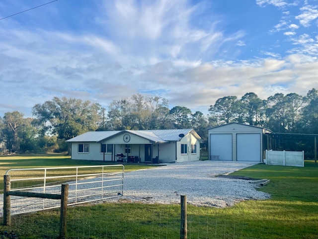 single story home featuring a garage, a front lawn, an outbuilding, and a porch