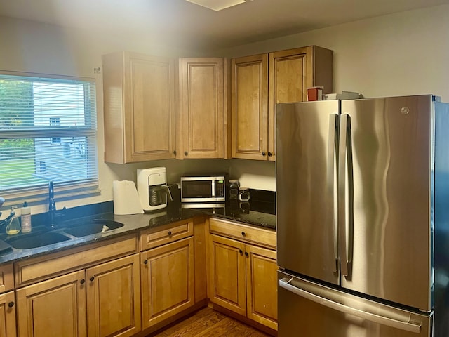 kitchen with dark wood-type flooring, sink, dark stone countertops, and stainless steel appliances