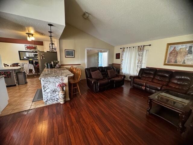 living room with vaulted ceiling, light hardwood / wood-style floors, and a textured ceiling