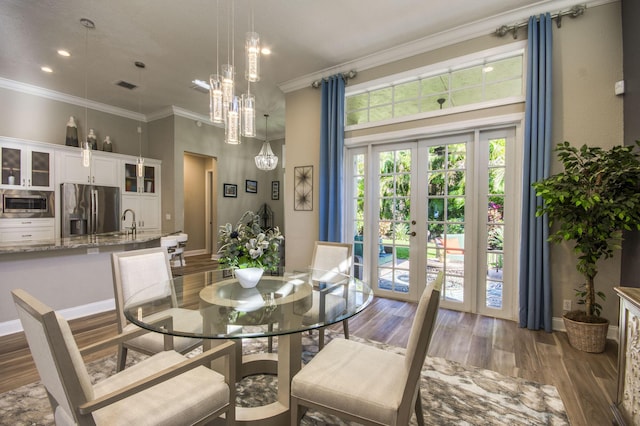 dining room with a towering ceiling, sink, crown molding, dark wood-type flooring, and french doors