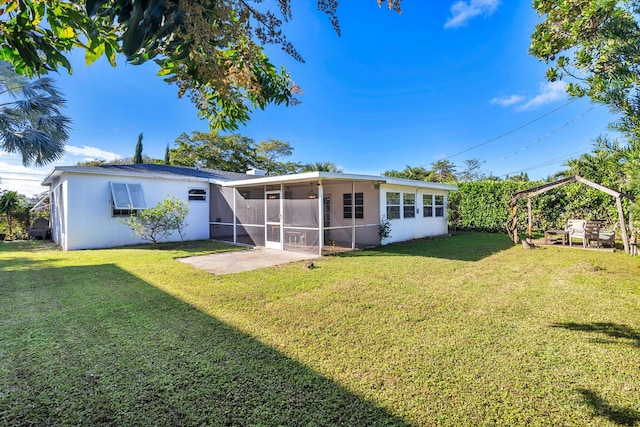 rear view of house featuring a lawn, a patio area, and a sunroom