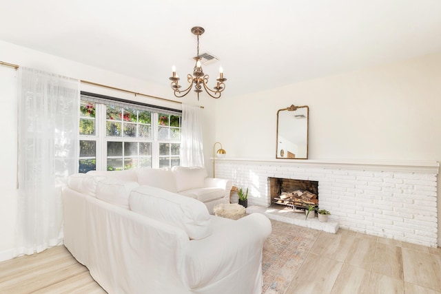 living room with a brick fireplace, light hardwood / wood-style floors, and an inviting chandelier