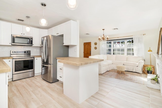 kitchen with wood counters, decorative light fixtures, decorative backsplash, white cabinets, and appliances with stainless steel finishes