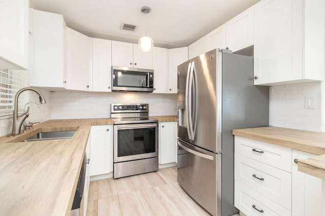 kitchen with white cabinets, stainless steel appliances, and butcher block counters