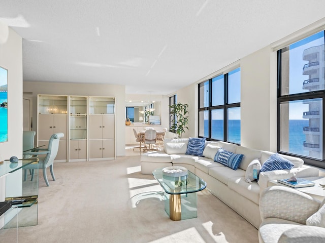 living room with a textured ceiling, floor to ceiling windows, a water view, and light carpet