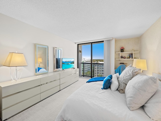 carpeted bedroom with access to exterior, a textured ceiling, and a wall of windows